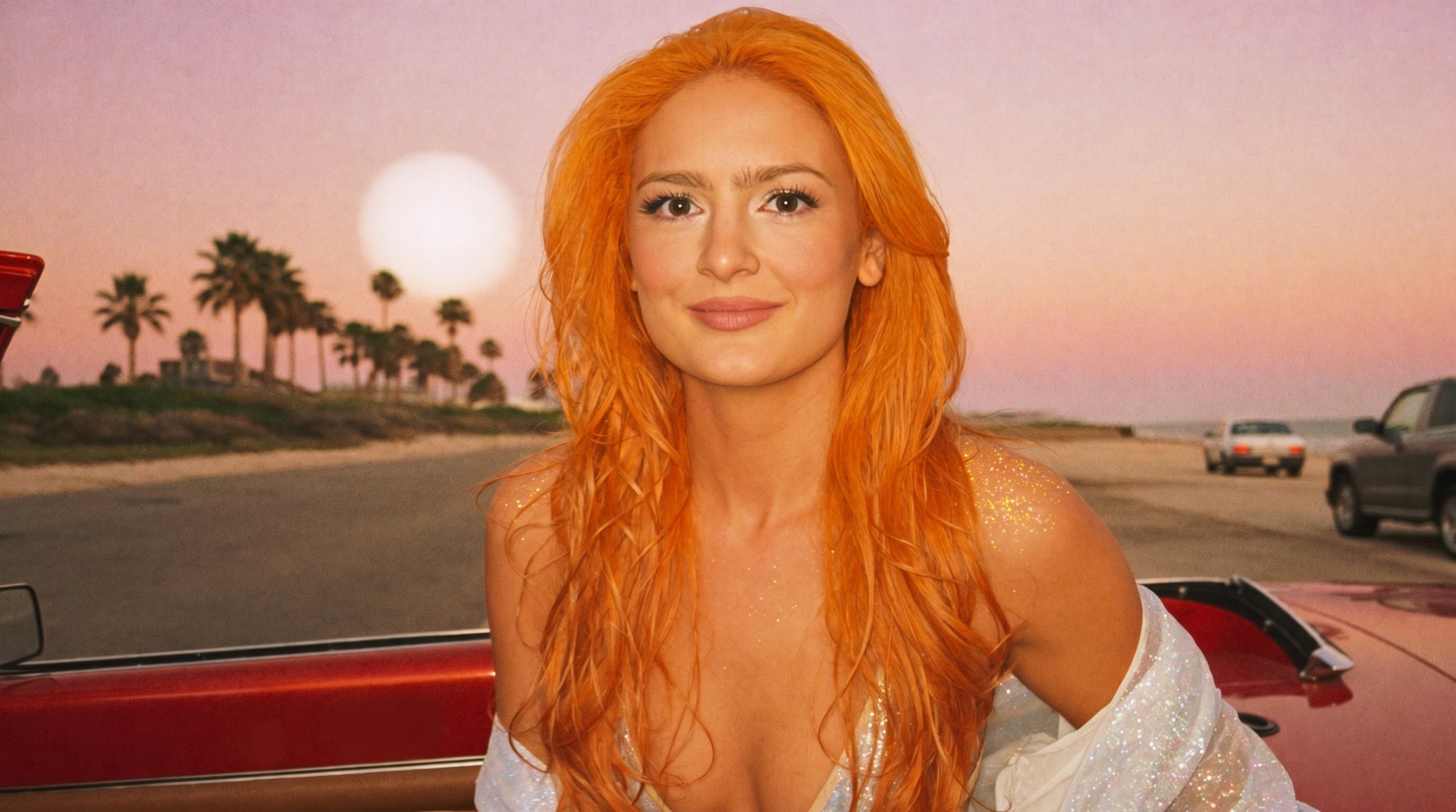 Orange-haired Carla in a white jacket by a red convertible on a beach road at sunset.