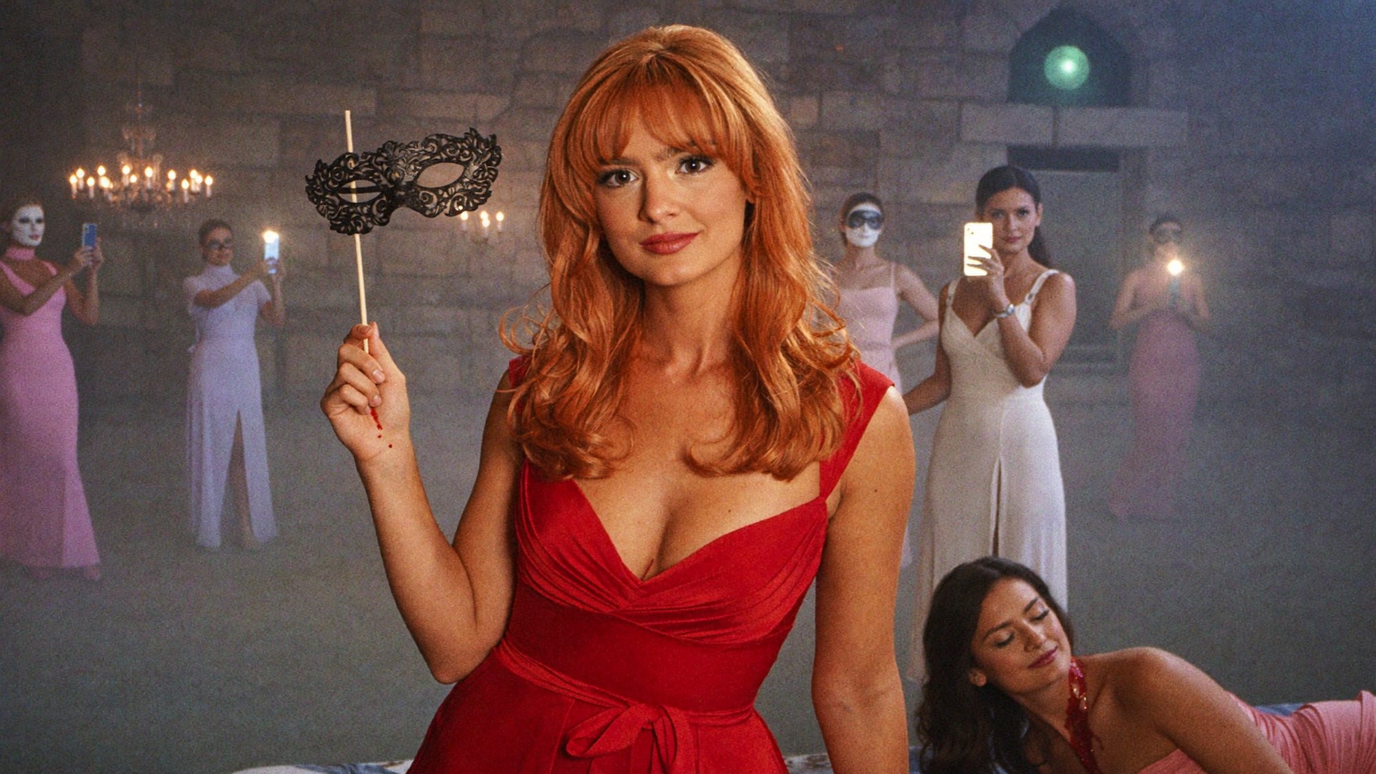 Orange-haired Carla in red holding a mask at a ball where influencers film on their phones.